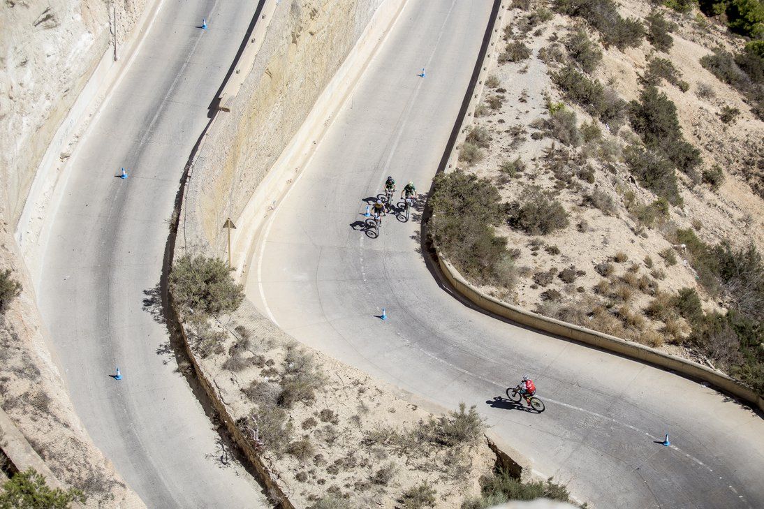 Vista desde lo alto de los ciclistas subiendo por una carretera en zigzag