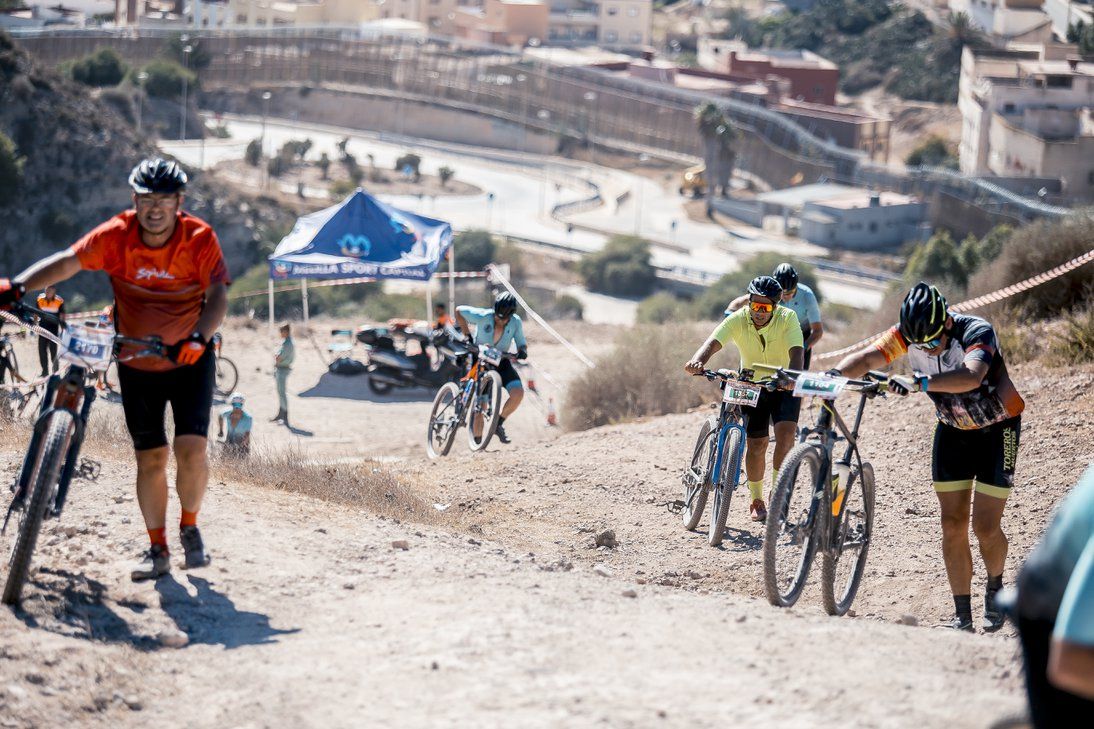 Ciclistas empujan sus bicicletas por una cuesta de tierra