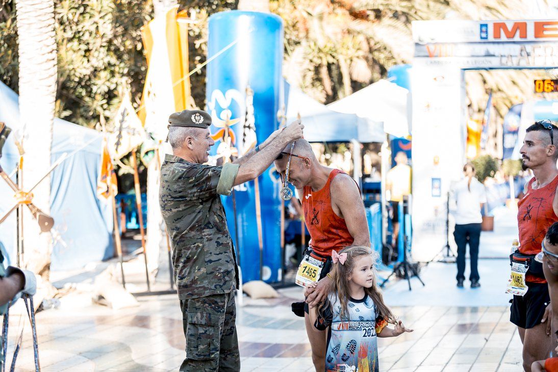 Un militar impone la medalla a una niña en la zona de meta