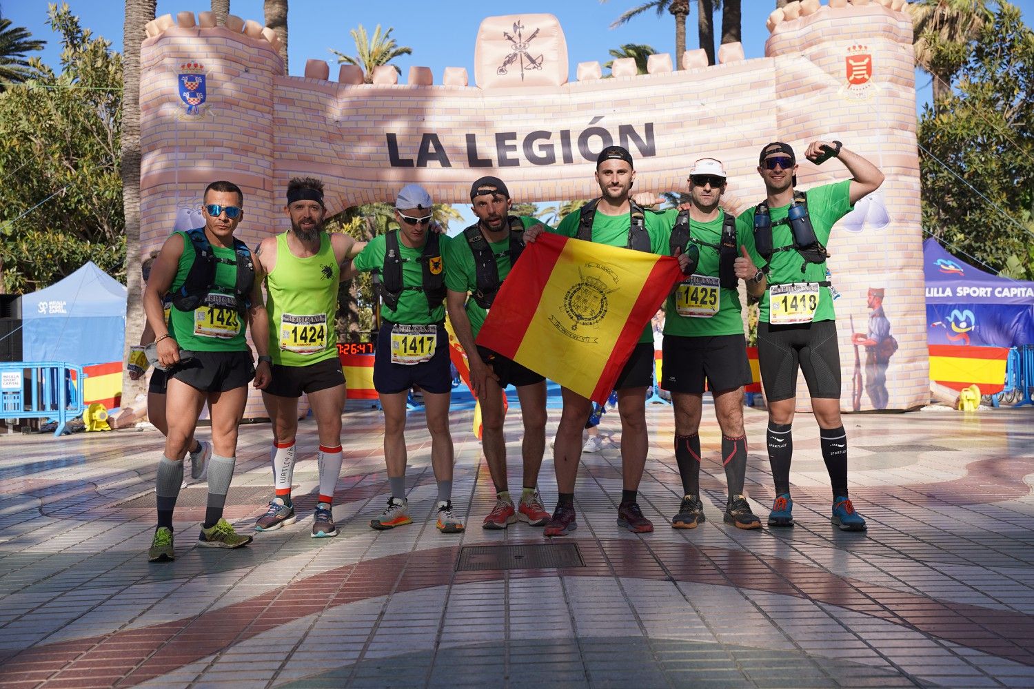 Un equipo celebra con una bandera bajo el arco de meta