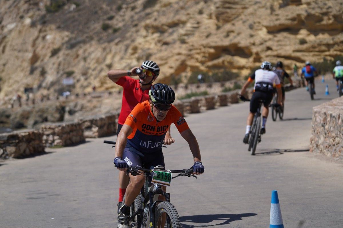 Un ciclista sube una cuesta junto a una pared de roca