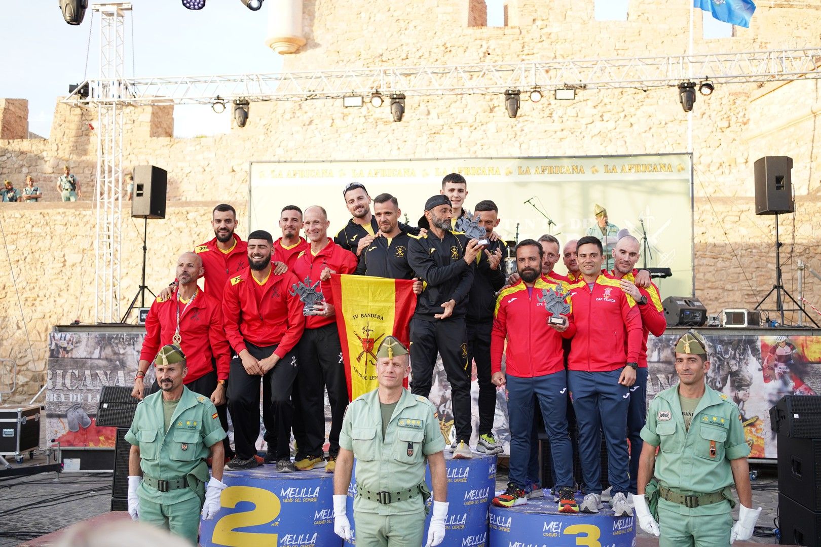 Un equipo recoge su trofeo en el podio con una bandera de España