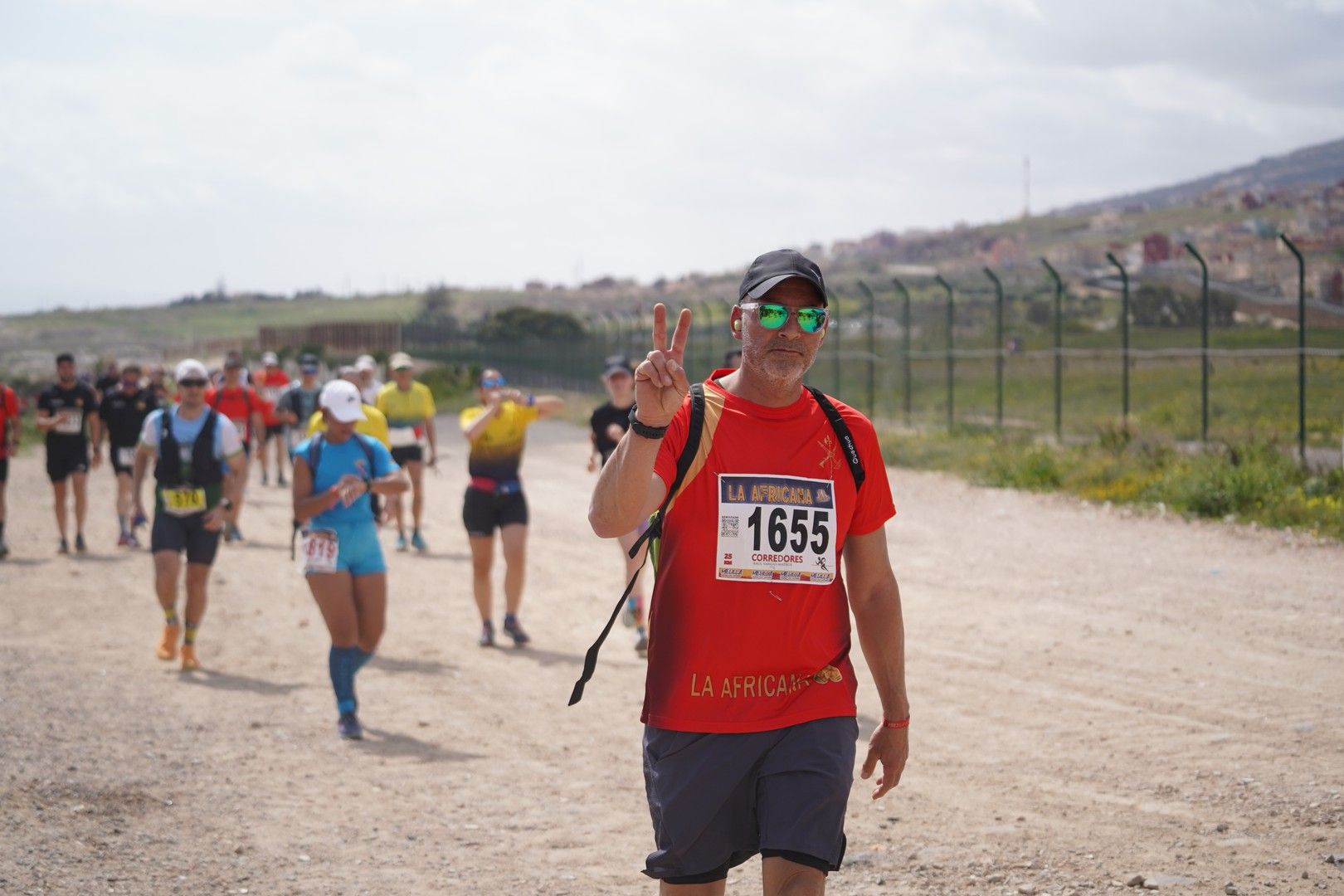 Un marchador saluda a la cámara en una pista de tierra