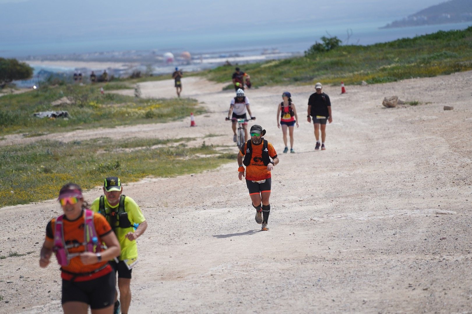 Corredores por un camino de tierra con el mar al fondo