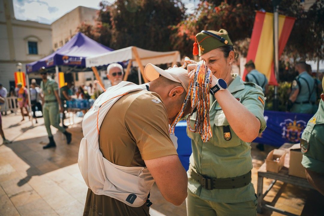 Una militar impone la medalla de finisher a un participante