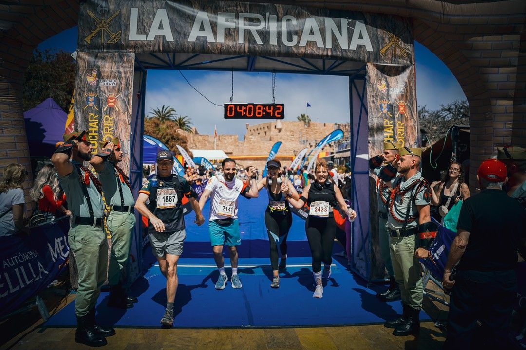 Marchadores cruzan el arco de meta de La Africana entre legionarios