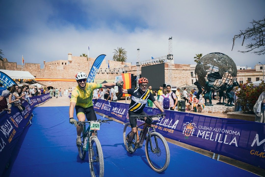 Dos ciclistas de BTT cruzan la meta frente a las murallas de Melilla la Vieja