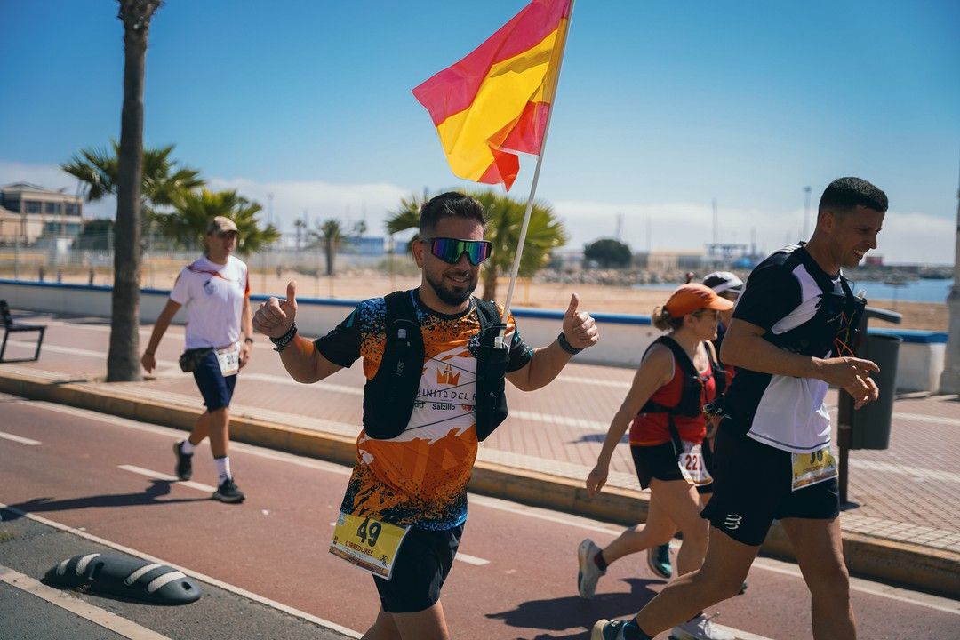 Un corredor levanta el pulgar en el paseo marítimo con una bandera de España al fondo